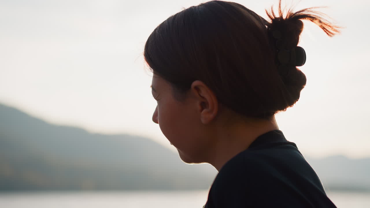 슬픈 여자가 일몰 클로즈업에서 자연에서 시간을 보내고, 따뜻한 가을에 산의 숨막히는 전망을 쳐다보며 사려 깊게 보입니다.