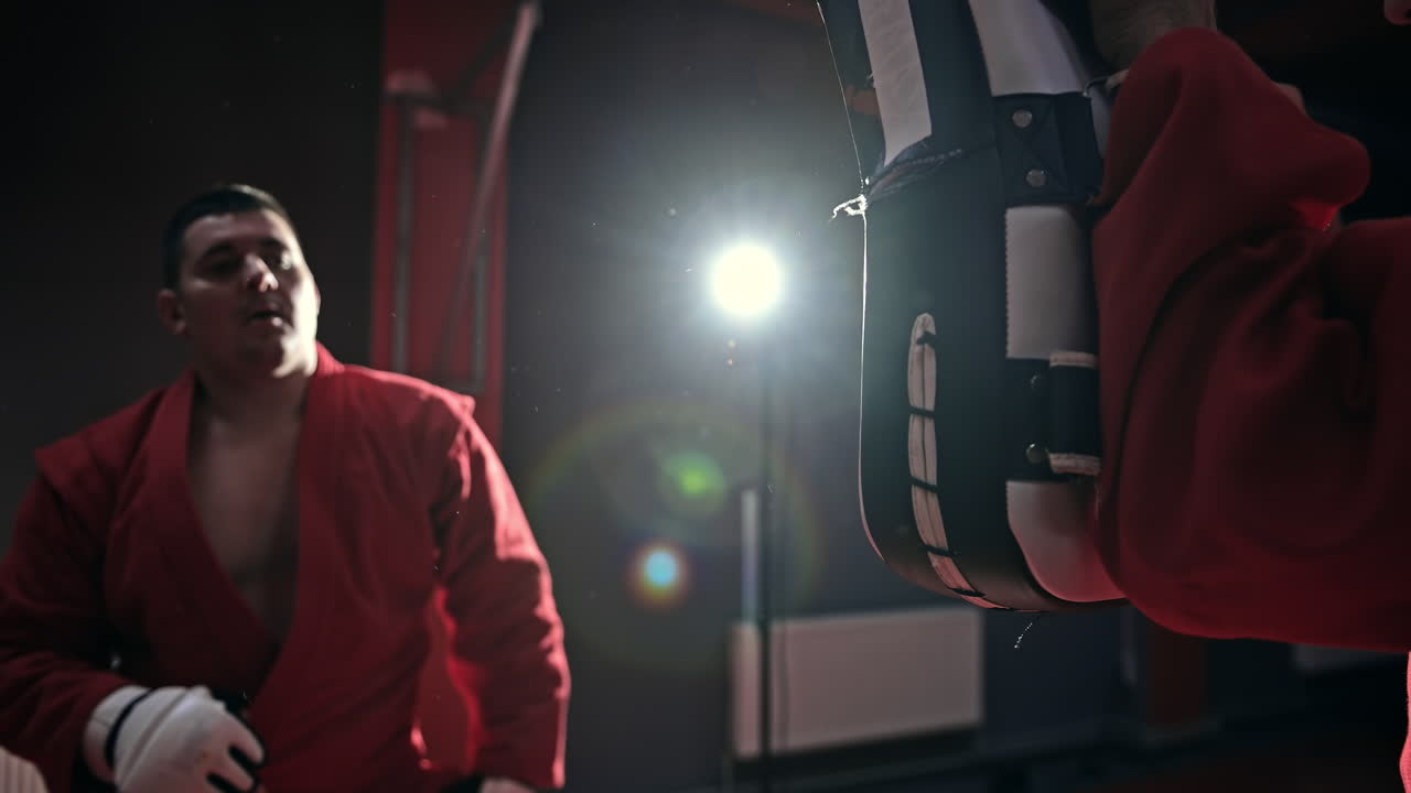 Taekwondo practitioner in a red kimono is training in a gym