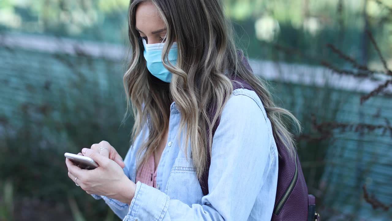 una mujer con una máscara marca su teléfono durante la epidemia pandémica del coronavirus covid19
