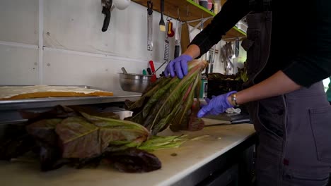 Food-worker-gathers-vegetables-on-cutting-board