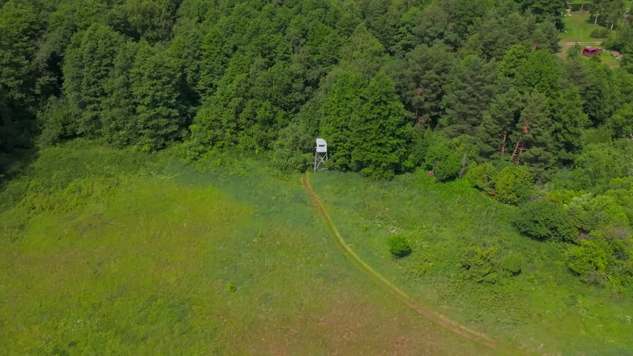 Birdwatching observation post at the edge of a forest by a field, left to right movement