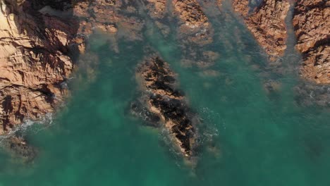 Aerial-Stationary-Shot-Of-A-Rock-Formation-Getting-Hit-By-Small-Waves