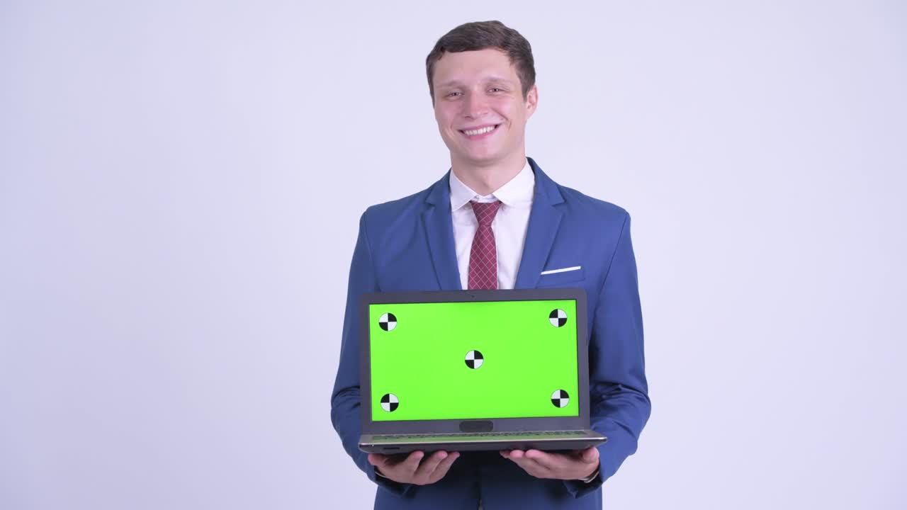 feliz joven hombre de negocios guapo en traje con computadora portátil