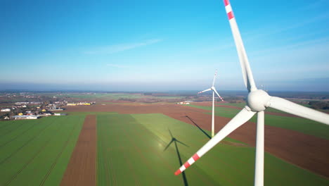 Rotating-wind-turbines-on-field---close-up-aerial