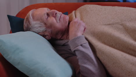 tired one senior old man lying down in bed taking a rest at home, napping, falling asleep on sofa