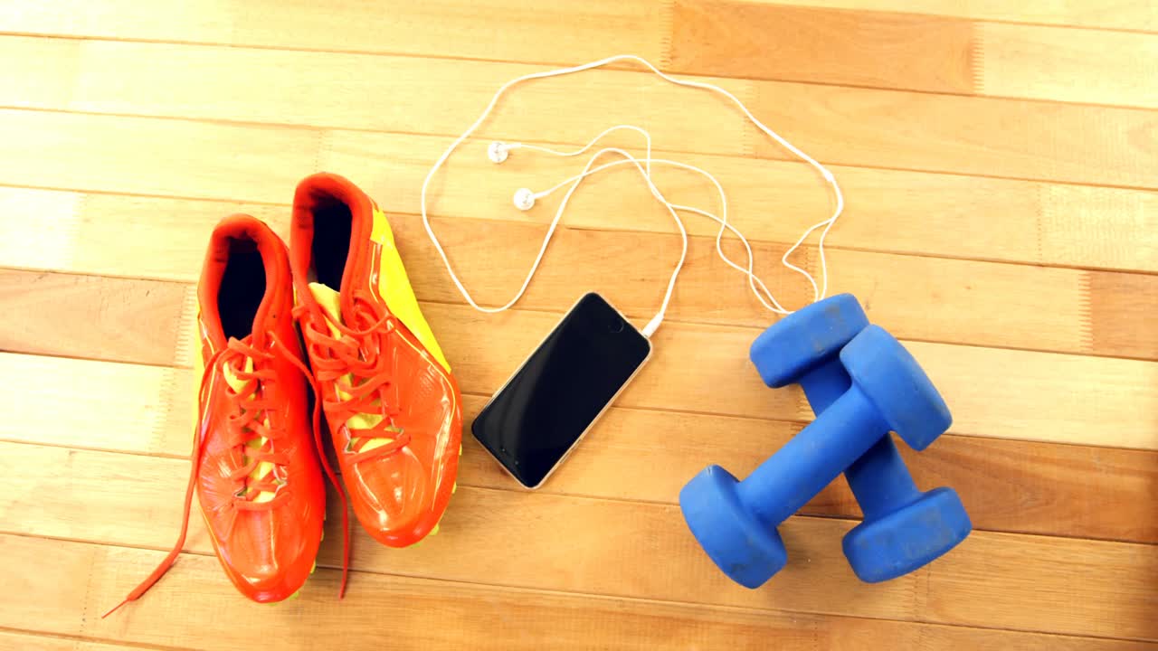 Ponsel dengan headphone, sepatu, dan dumbbell