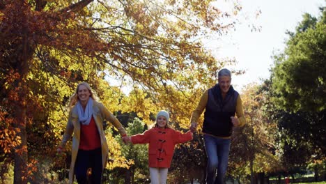 mother dad and daughter running hand in hand outdoors