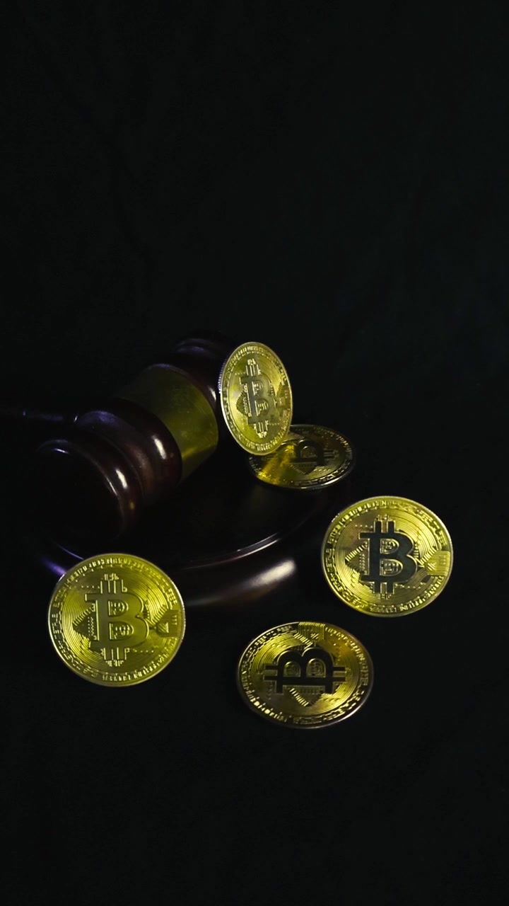 Bitcoins dourados e um martelo de juiz de madeira sobre um fundo preto, representando os aspectos legais, regulamentação e justiça em torno de criptomoeda, finanças e tecnologia blockchain