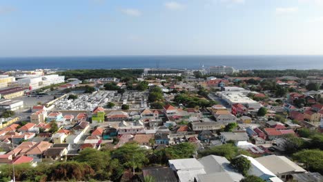 Panorámica-Aérea-A-Través-De-Vibrantes-Tejados-De-Color-Naranja-En-Willemstad-Curazao,-Vista-Al-Mar.