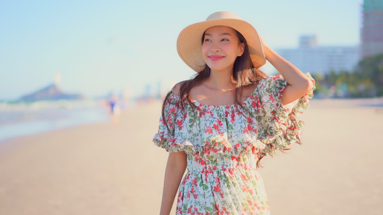 Asian female tourist posing on a beach with sun hat in slow motion