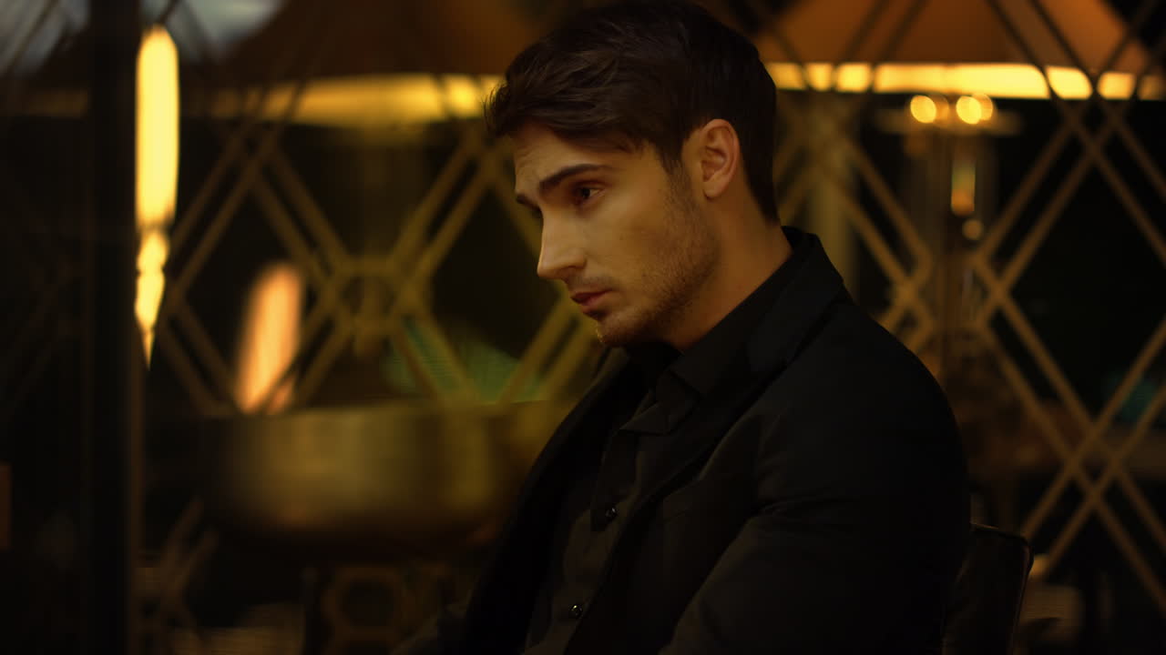 집 안에 의자에 앉아 있는 자신감 있는 남자. 주위를 둘러보는 우아한 남자.