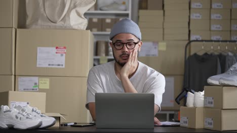un empresario asiático exitoso, un joven sonriente, un vendedor en línea que toma nota de los pedidos de los clientes, un dueño de un negocio de dropshipping que trabaja en su almacén.
