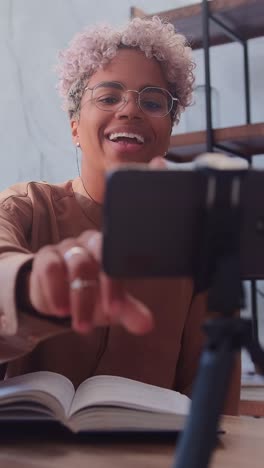 young african american woman recording video on phone and waves hand friendly