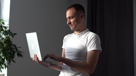 Young-man-talking-on-video-calling-in-headphones-at-his-laptop-at-home-in-the-living-room