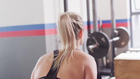 video of rear view of caucasian woman working out at a gym doing kettlebell swings