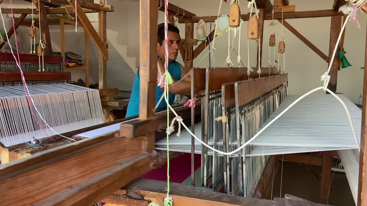 Skilled weaver making intricate fabrics on a loom in a Mexican factory store.