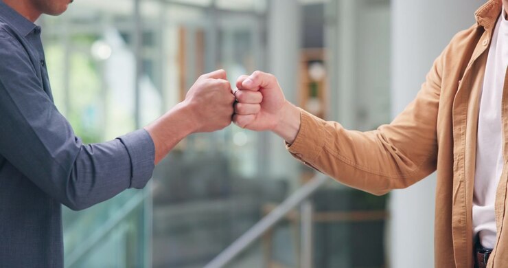 Two Men Greeting Each Other With A Fist Bump In An Office
