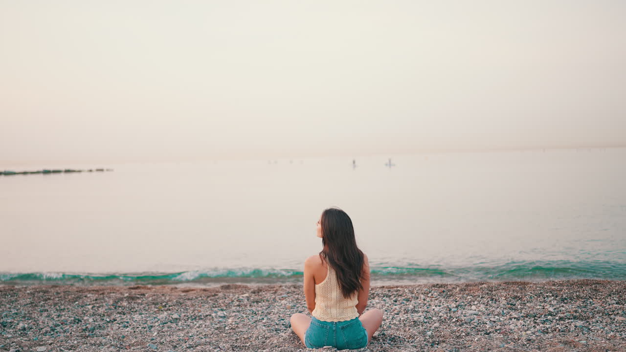 Woman sitting on a beach enjoying the sunrise