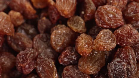 raisins cascade onto a pile in a macro close-up, showcasing texture and movement against a white background