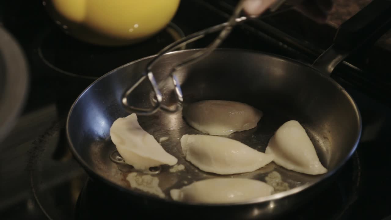 Frying Dumplings And Turning The Sides Using A Stainless Steel Tong - Close Up Shot
