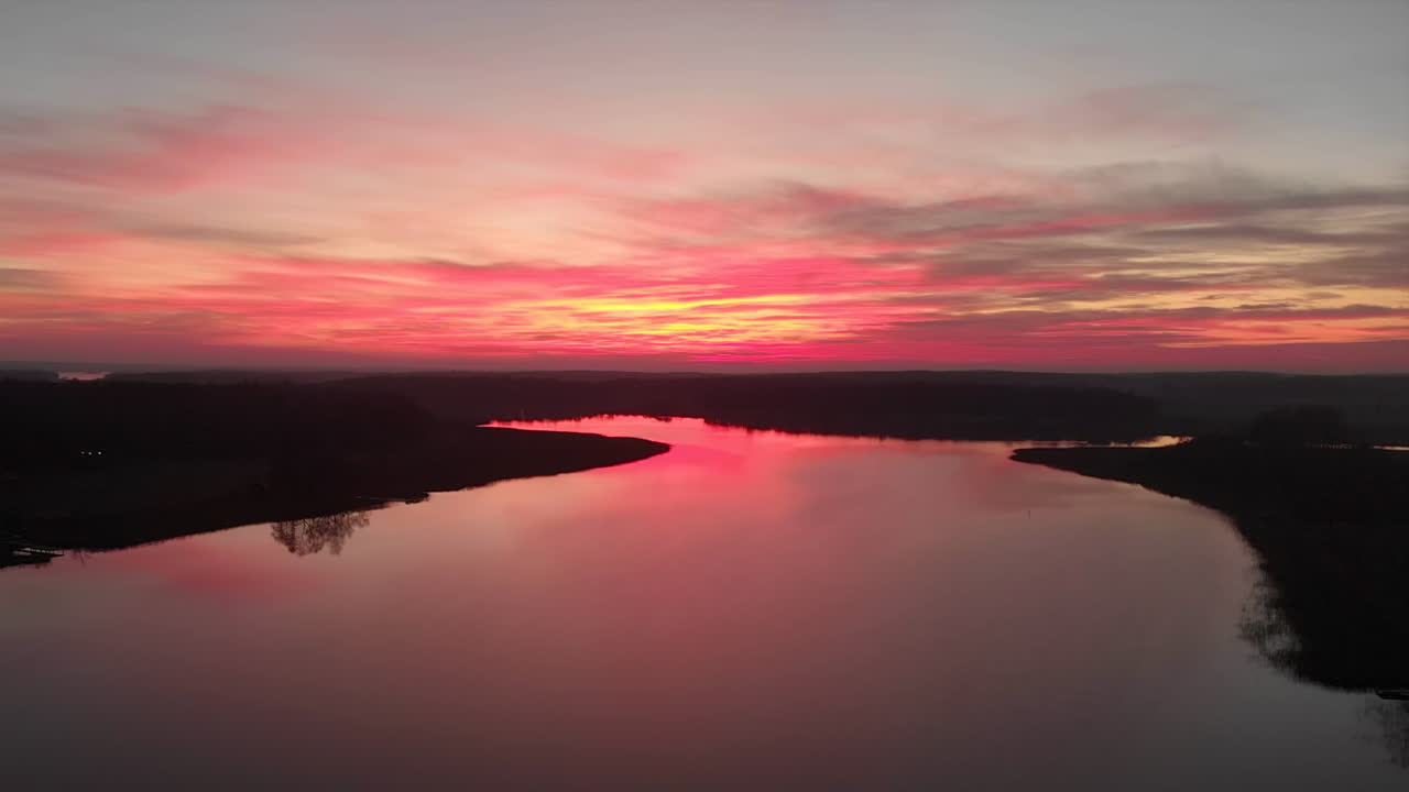imágenes de drones volando hacia una impresionante puesta de sol con un lago debajo