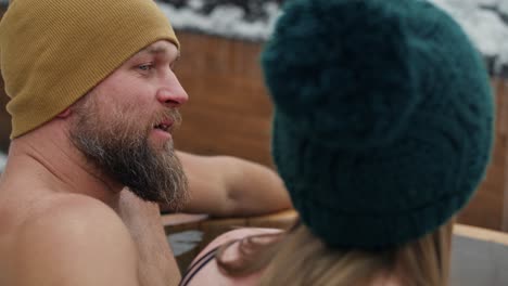 caucasian woman with man talking together during the winter bath in frozen water.