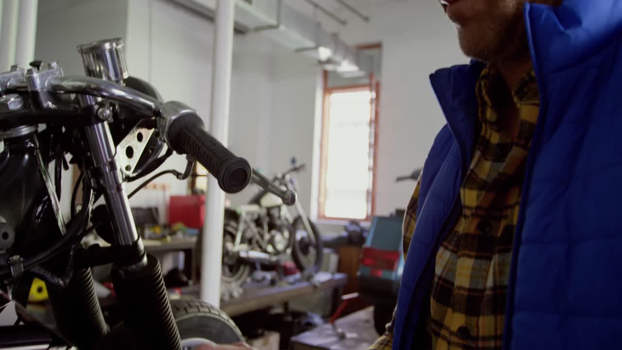 mecánico masculino que usa una tableta digital en un garaje de reparación de motocicletas 4k