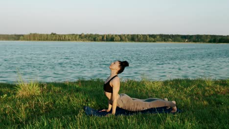 brunette woman practicing yoga in park. girl doing yoga moves on green grass