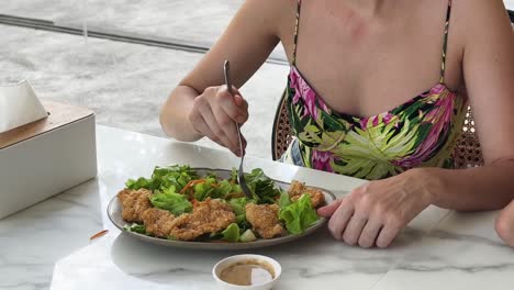 woman eating salad with fried chicken