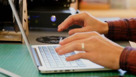 mecánico sosteniendo un anillo de cadena mientras usa una computadora portátil en el escritorio 4k