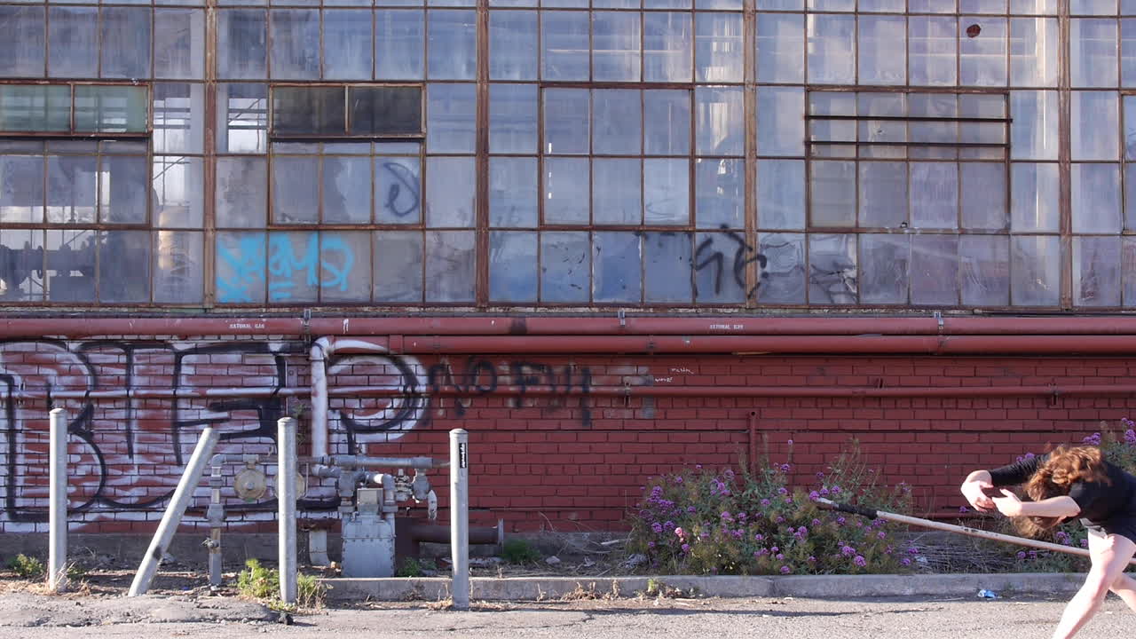 Dança interpretativa de mulher em frente a um armazém industrial abandonado de tijolos vermelhos
