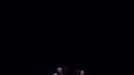 un cielo nocturno oscuro se transforma con coloridos rayos de luz y fuegos artificiales que explotan