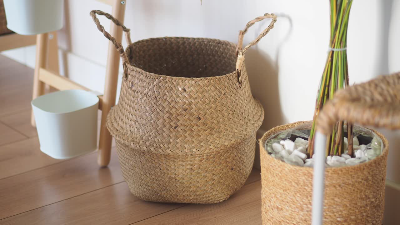 木製の床に置かれた編み込みバスケットと緑の植物