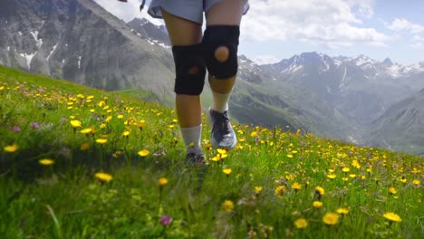 athletic woman hiking with knee pads in alpine valley full of flowers