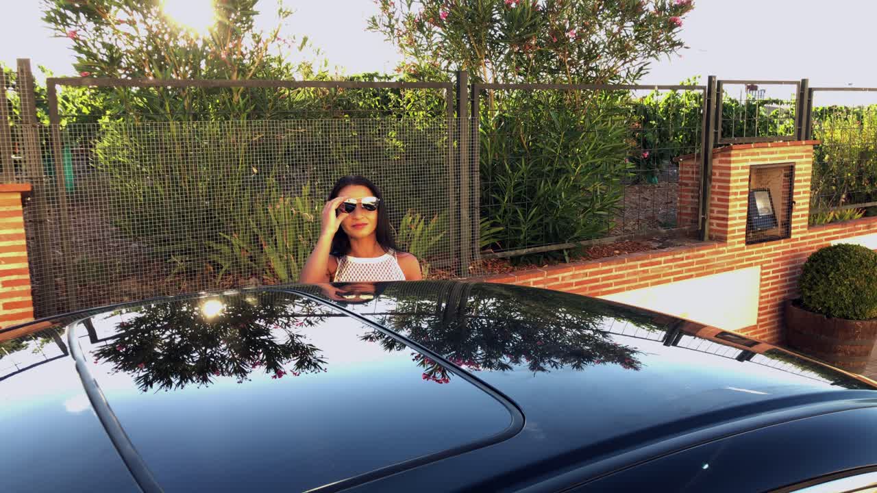 mujer saliendo del auto y quitándose las gafas de sol