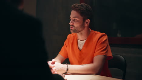 man in orange jumpsuit at interrogation