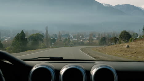 front window of car driving on a highway surrounded by mountains
