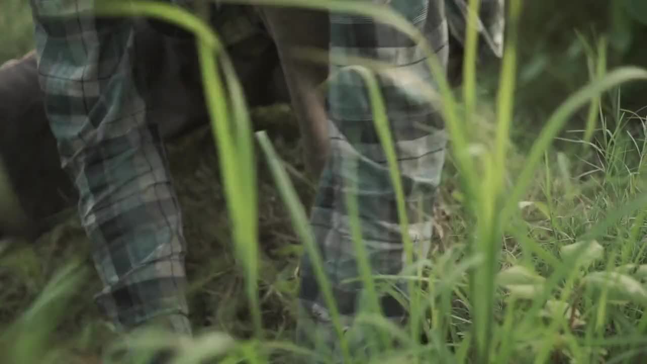 An Indonesian man diligently digs soil in a vibrant Bali rice field, bathed in warm, natural light. The close-up captures his focused effort amidst lush green rice plants.