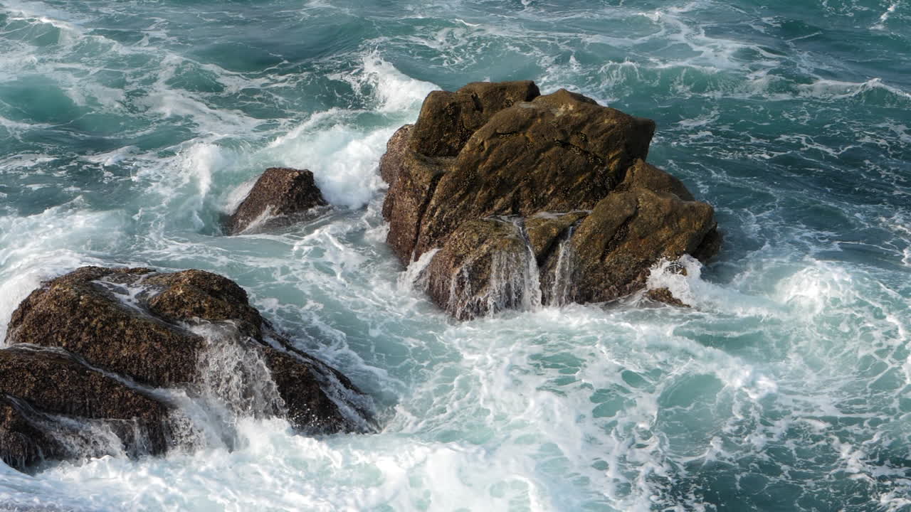 Dettaglio di roccia costiera semisommersa e onde oceaniche impetuose e spumeggianti