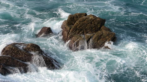detalle de la roca costera medio sumergida y las olas del océano espumosas salvajes