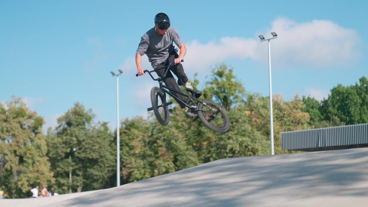 Giovane uomo che esegue un salto in BMX al rallentatore allo skatepark