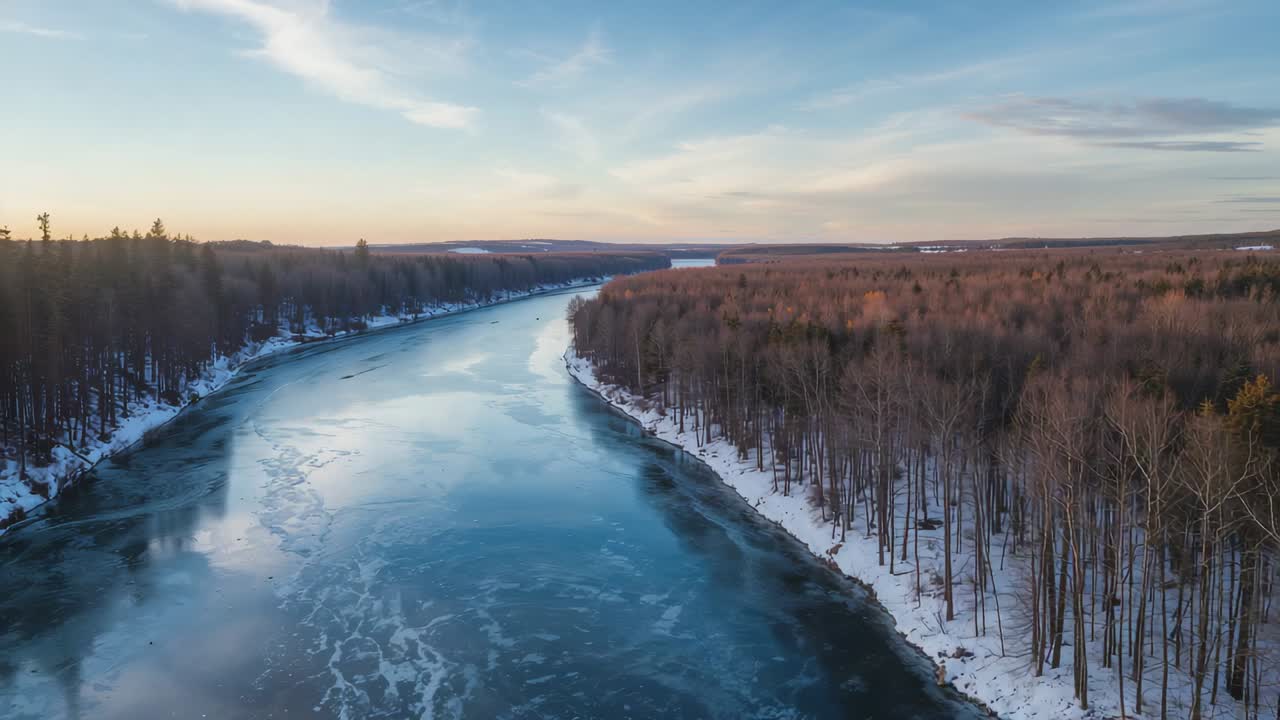Gliding drone camera revealing winding river in winter valley, capturing ice floes and snow