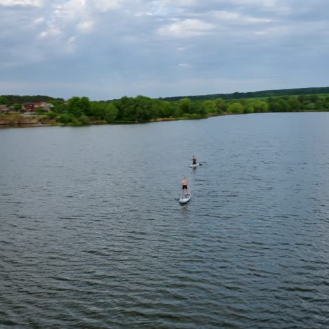 young people doing sport on water. travelling on boards on river on beautiful summer landscape in the countryside. leisure time in summer. aerial view