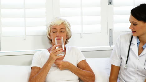 nurse giving medicaments to a senior woman
