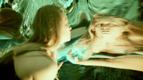 woman looking at her distorted reflections in mirror surface under vivid light