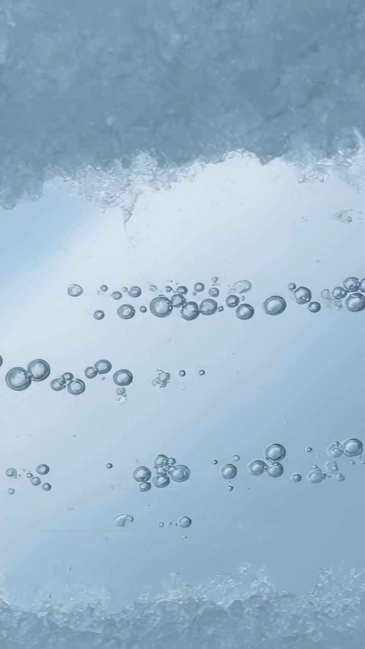 Video verticale: Bolle in ascesa che si muovono in una colonna d'acqua, con ghiaccio superiore e inferiore che si scioglie rilasciando aria.