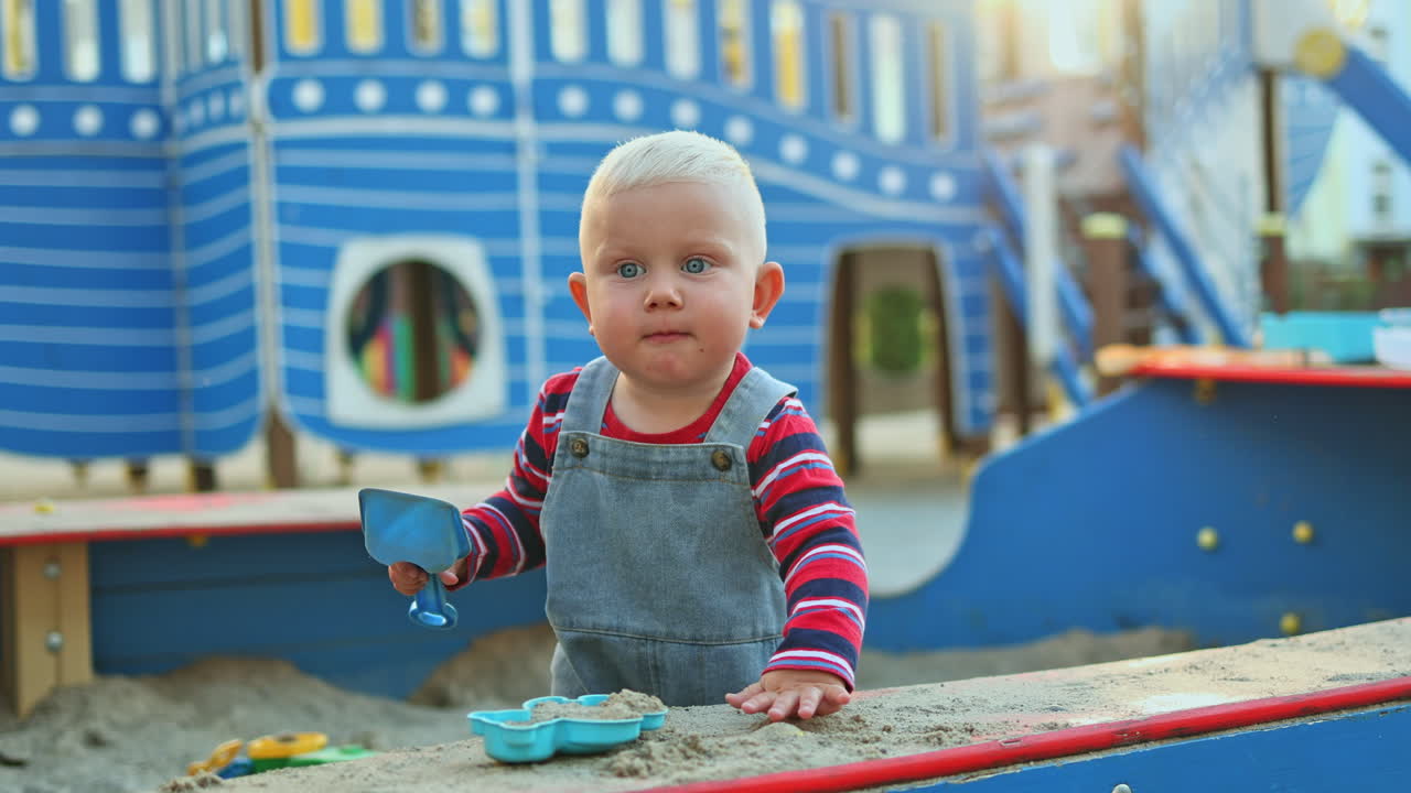 Baby boy playing with sand outdoors. Child development. Children's games on the playground