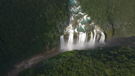 Aerial-tilts-down-Tamul-waterfall-as-cascading-water-falls-into-turquoise-river-in-Mexican-Jungle