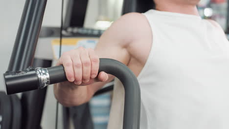 muscular man seated on cable machine grips handle and pulls weight with controlled motion, muscles contracting under bright gym lighting in modern fitness environment showcasing strength and form