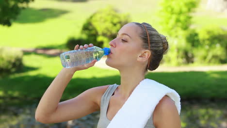 a woman takes a drink of water as the camera changes to a side view